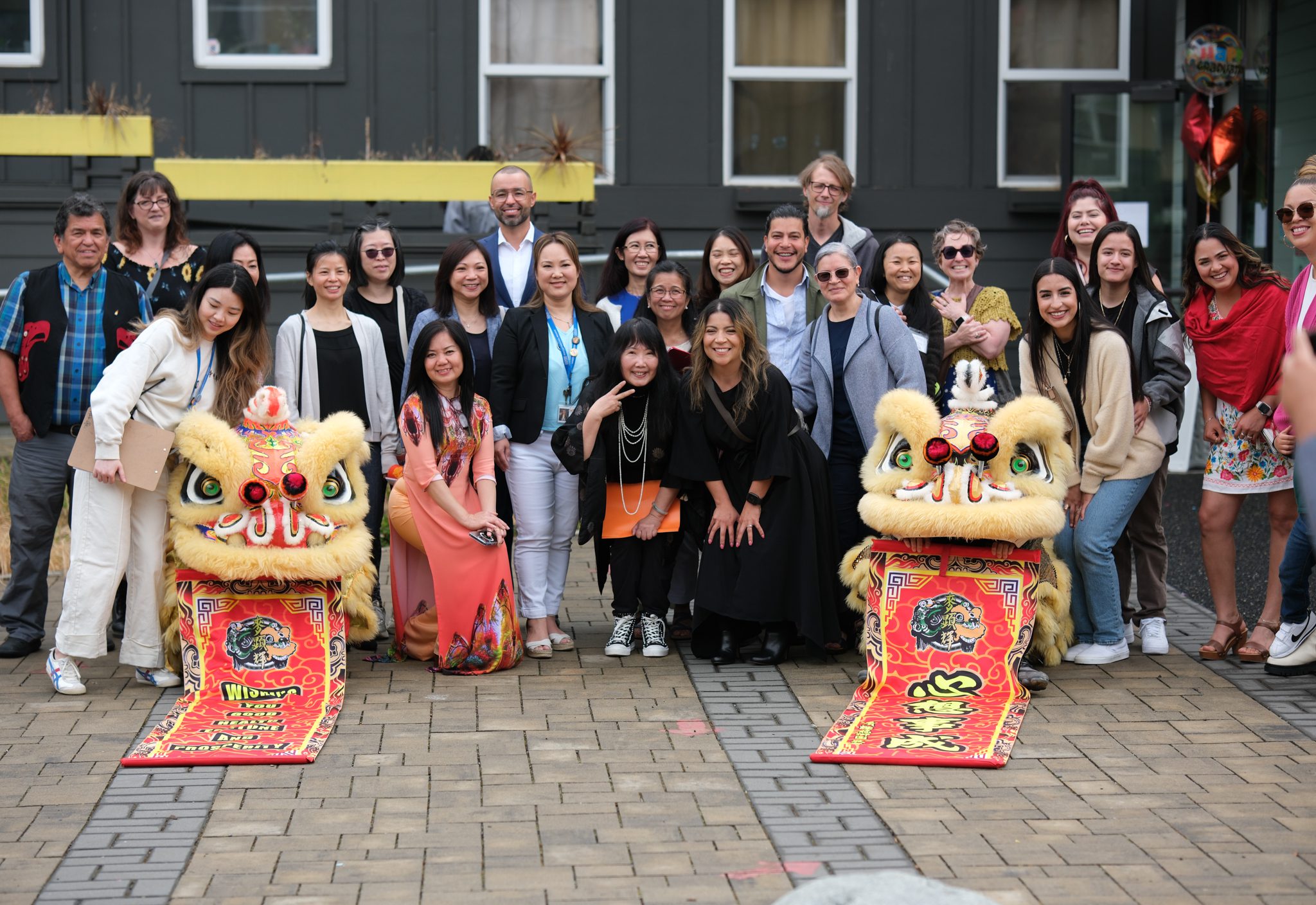 Early learning teachers representing the Seattle Preschool Program Dual-Language Initiative pose for a photo with DEEL staff and Mak Fai lion dancers.