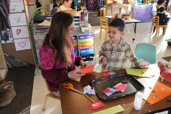 Preschool teacher and child doing an arts and craft activity.