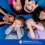 Children in a circle smiling and covering their eyes.