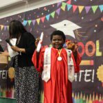 A smiling child wearing a graduation gown.