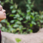 Profile of a high school aged youth of color wearing a plaid shirt sitting outdoors